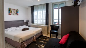 A hotel room with a bed, a chair, a TV, and a window with curtains. - Hôtel de l'Europe (Paris)
