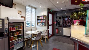 A café with a vending machine, tables, chairs, a potted plant, and a fire extinguisher. - Hôtel de l'Europe (Paris)