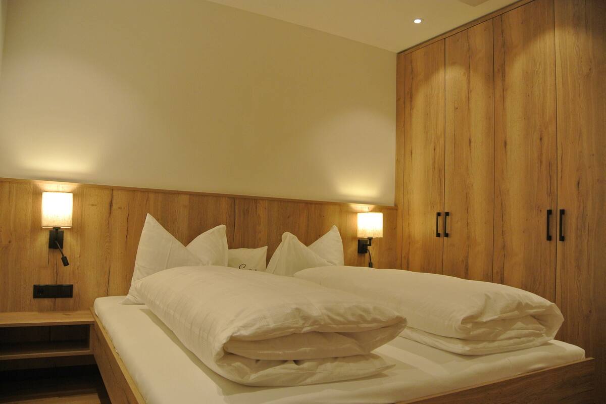 Un dormitorio con cabecera de madera, dos lámparas de noche y un armario grande.