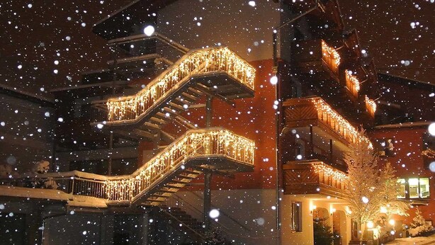 Ein mehrstöckiges Gebäude mit einer Treppe, die von warmem Licht erhellt wird, umgeben von Schnee.