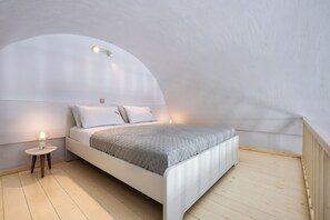 A bedroom with a bed, bedside tables, and a curved ceiling. - Sigal Villa (Santorini)