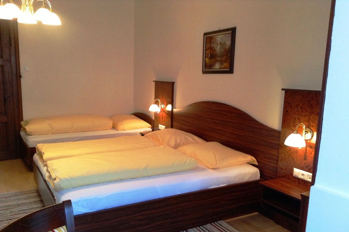 A hotel room with a wooden bed, two bedside tables, and a painting on the wall.