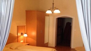 Una camera d'albergo con un letto in legno, una sedia rossa e una lampada a soffitto.