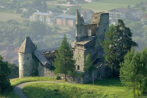 A medieval castle with a tower, surrounded by greenery and a pathway. - Gasthof Post (Oberdrauburg)