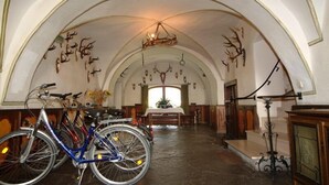 Un corridoio ad arco con un lampadario, un tavolo con sedie e biciclette.