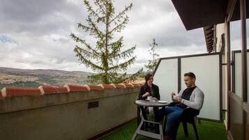 Dues persones assegudes a una taula en una terrassa al terrat amb vista al paisatge.