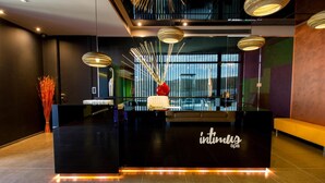 A reception desk with a black counter and the name "intimilis spa" in white letters. There are three pendant lights above the counter, and a vase with red flowers on the counter. - Hotel & Spa Balfagón (Cantavieja)