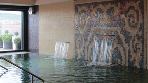 A large indoor pool with a mosaic wall and a waterfall feature. - Hotel & Spa Balfagón (Cantavieja)