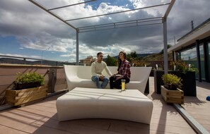 A modern outdoor seating area with a white sofa and wooden planters. - Hotel & Spa Balfagón (Cantavieja)