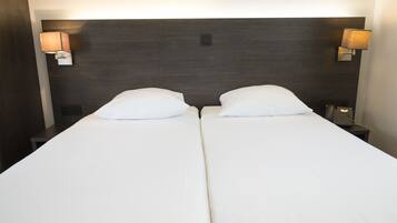 A double bed with white linens, two bedside tables with lamps, and a dark headboard.