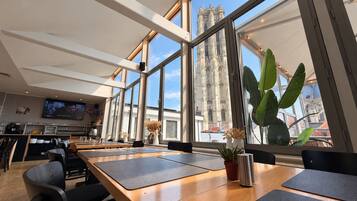 Een moderne eetruimte met grote ramen, een flatscreen televisie en uitzicht op een historische kathedraal.