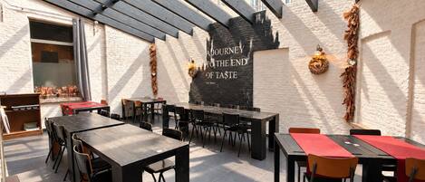 Un espace de restauration en plein air avec plusieurs tables et chaises, un tableau noir avec du texte et des éléments décoratifs.
