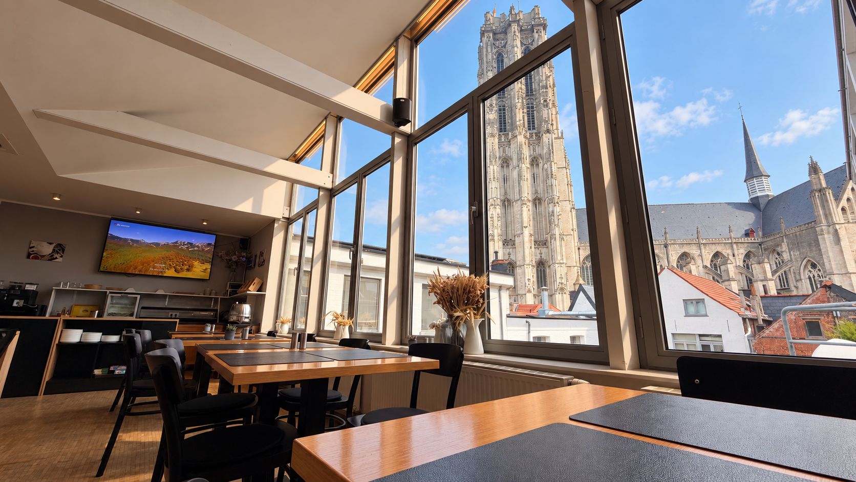 Un intérieur moderne avec de grandes fenêtres, un téléviseur à écran plat et une vue sur une cathédrale historique.