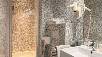 Een badkamer met een douche, toilet, wastafel en een prullenbak.