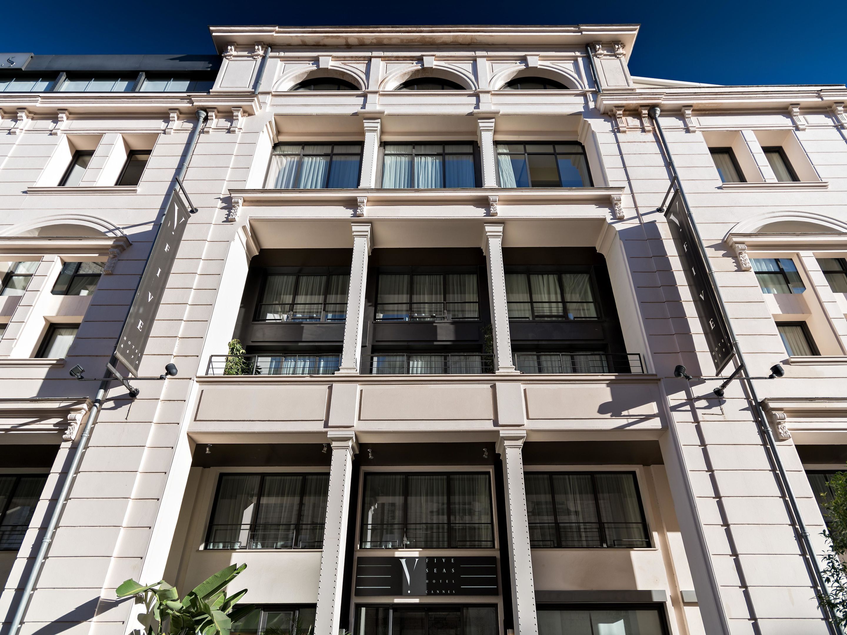 Un edificio de varios pisos con estilo arquitectónico clásico, que presenta grandes ventanales y un balcón en el segundo piso.