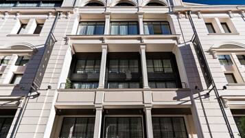 Un edificio de varios pisos con estilo arquitectónico clásico, que presenta grandes ventanales y un balcón en el segundo piso.