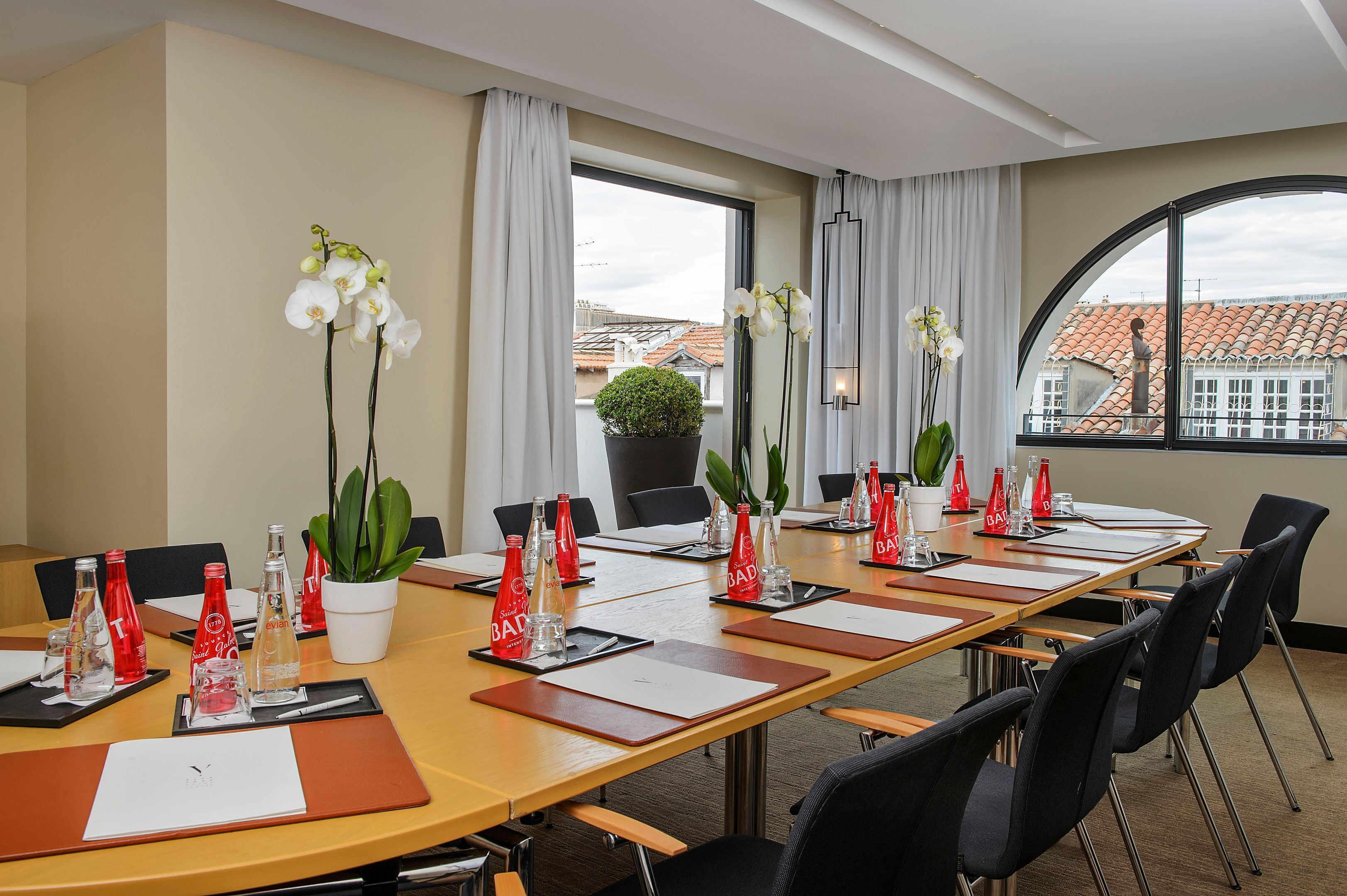 A conference room with a long table, chairs, and a potted plant.
