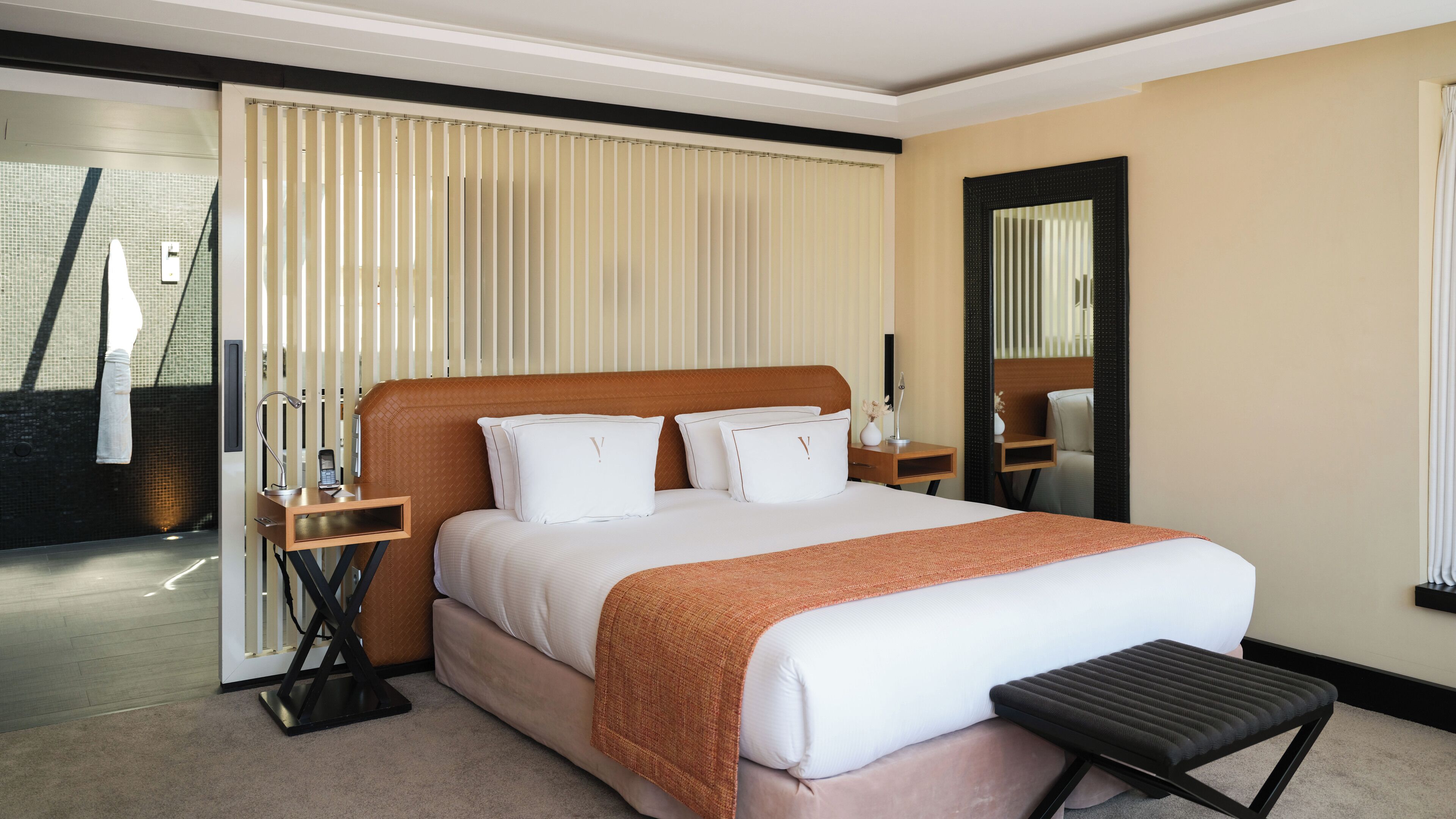 Une chambre d’hôtel avec un grand lit, une table de chevet, une commode, un miroir et une vue sur l’extérieur.