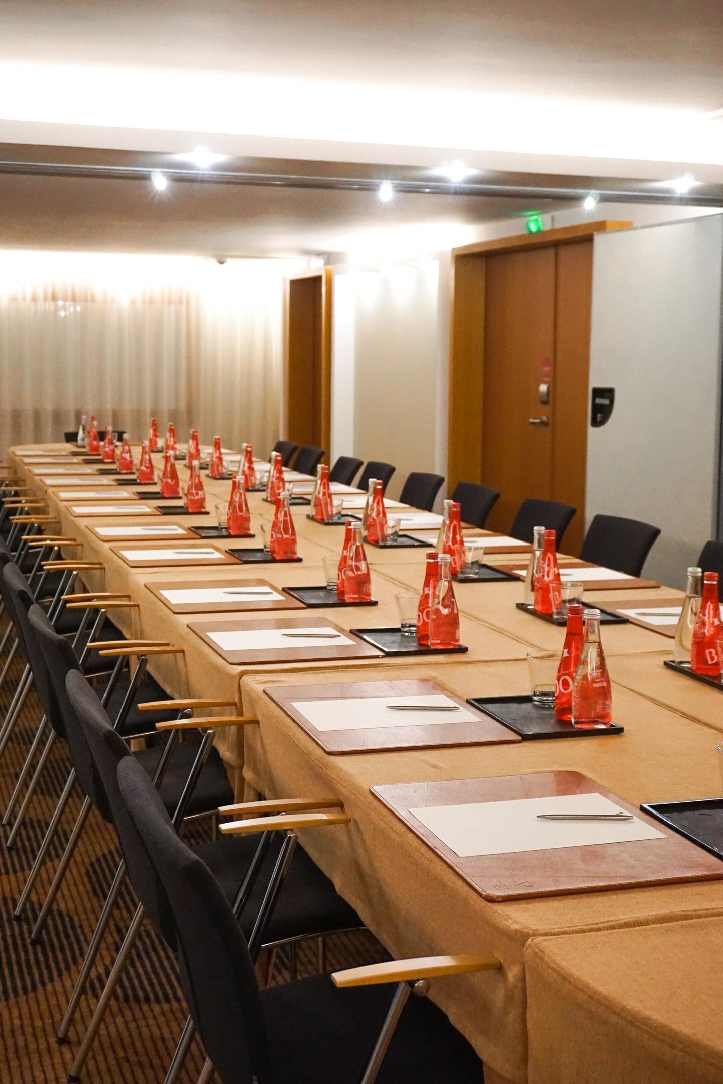 A conference room with long tables, chairs, and red water bottles.