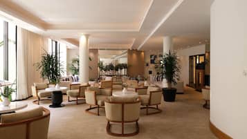 A hotel lobby with multiple seating areas, large windows, and potted plants.