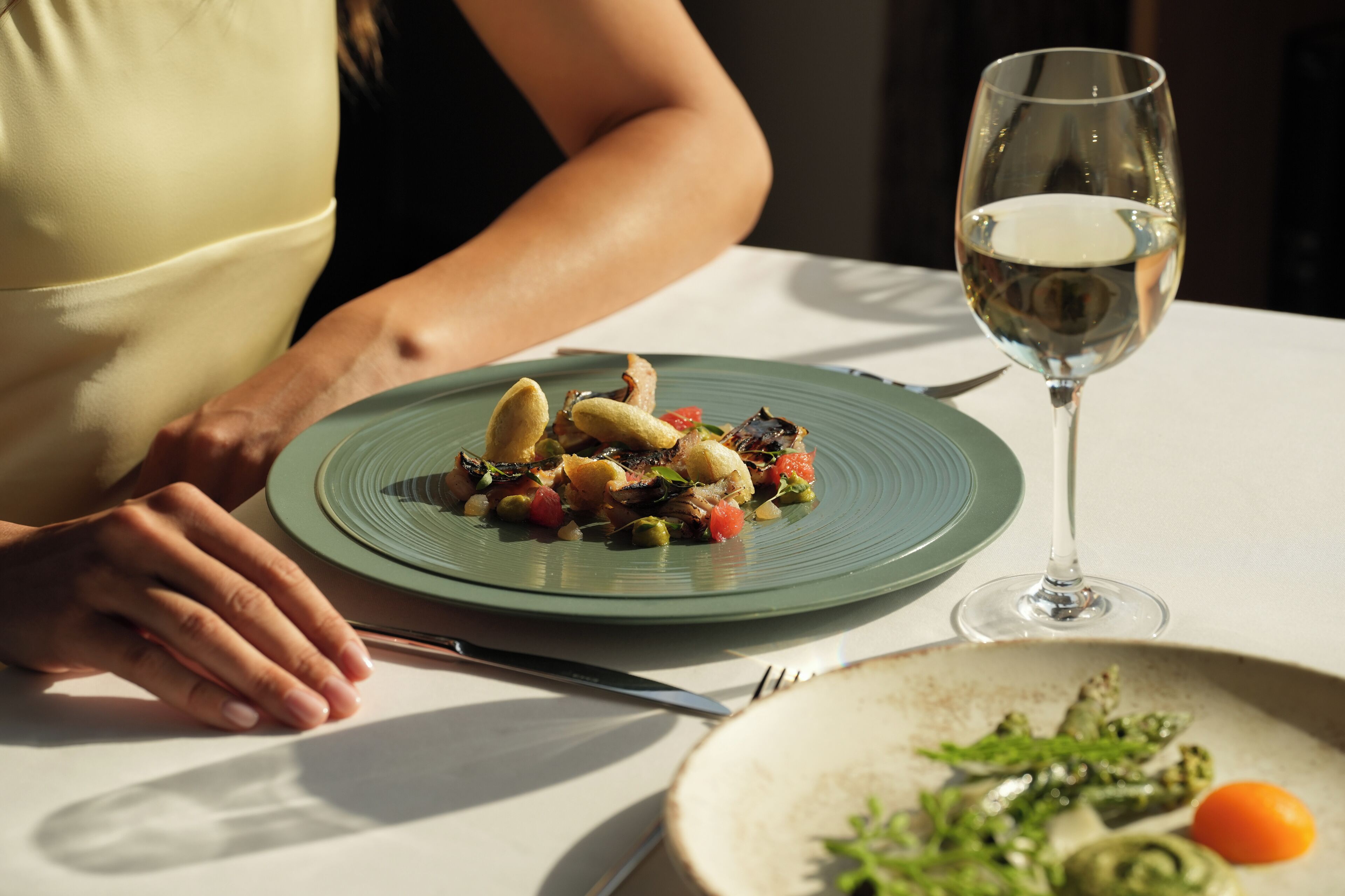 Una mesa de comedor con un plato de comida y una copa de vino.