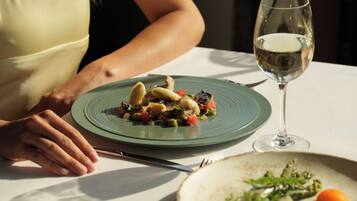 Una mesa de comedor con un plato de comida y una copa de vino.