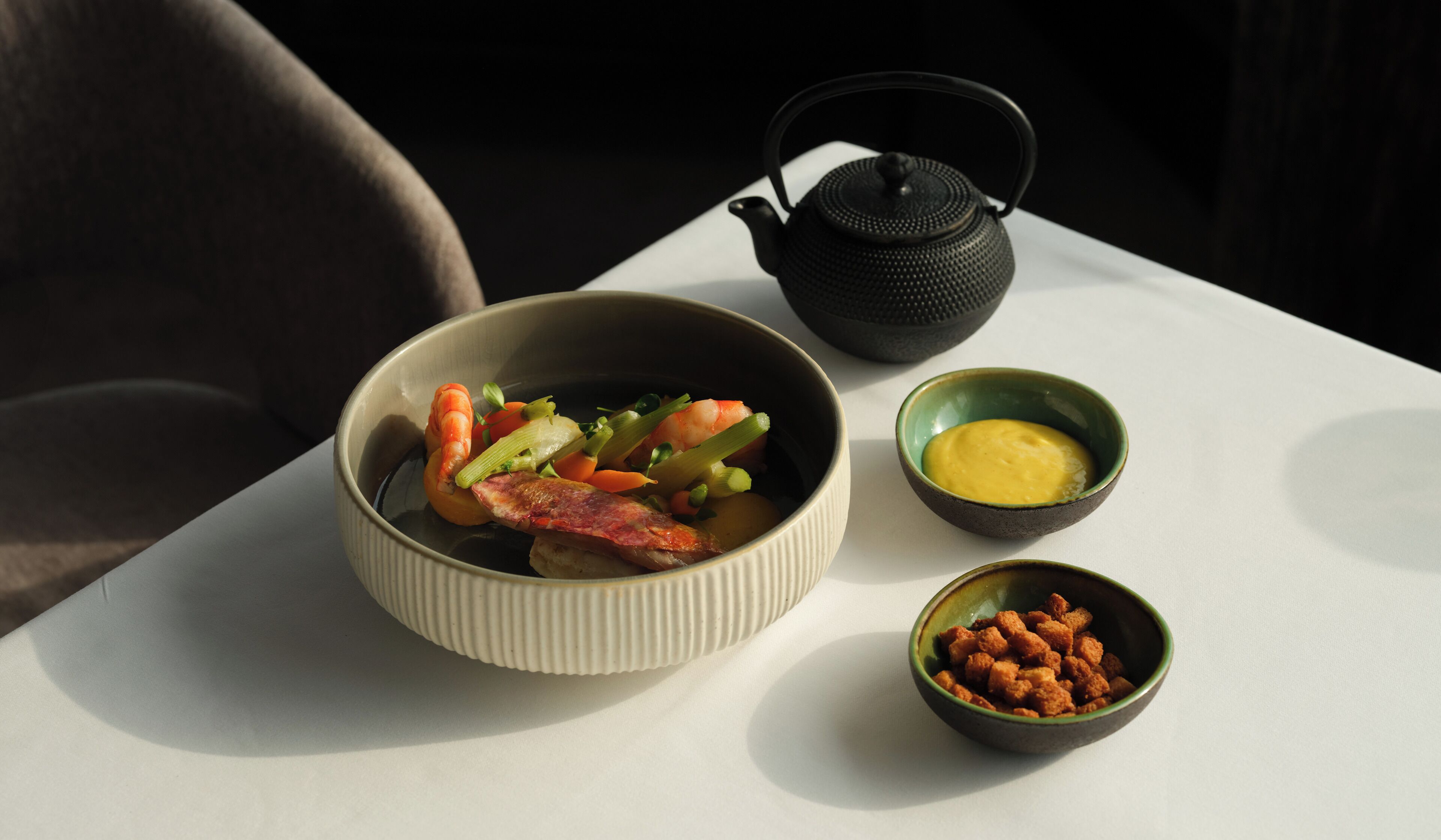 A table with a bowl of food, a teapot, and two small bowls.
