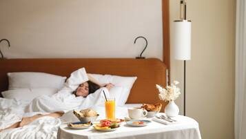 A hotel room with a bed, a bedside table with breakfast items, and a lamp.