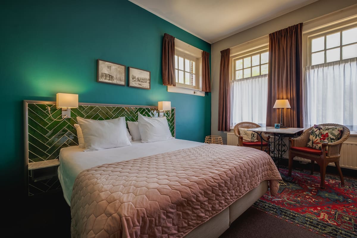 A hotel room with a large bed, a desk, and two chairs.