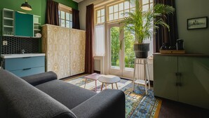 Una sala de estar moderna con un sofá, una mesita, un armario y un ventanal con vistas a zonas verdes.