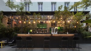 An outdoor bar area with a counter, bar stools, and string lights. - Petit Palace Santa Bárbara (Madrid)