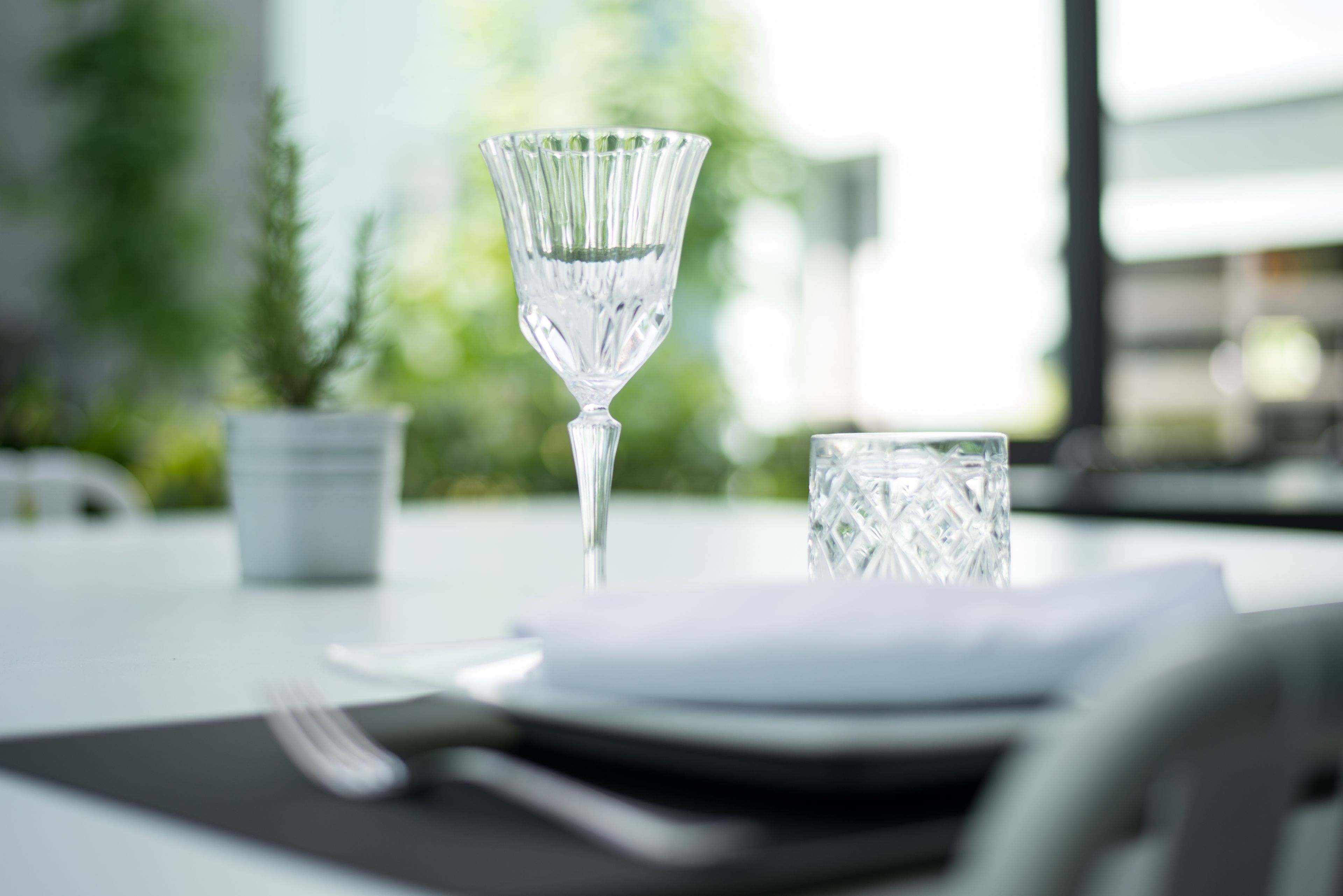 A dining table with a clear glass, a glass of water, and a folded napkin.