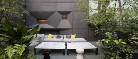 An outdoor seating area with a modern design, featuring a sofa set, two tables, and a small black table.