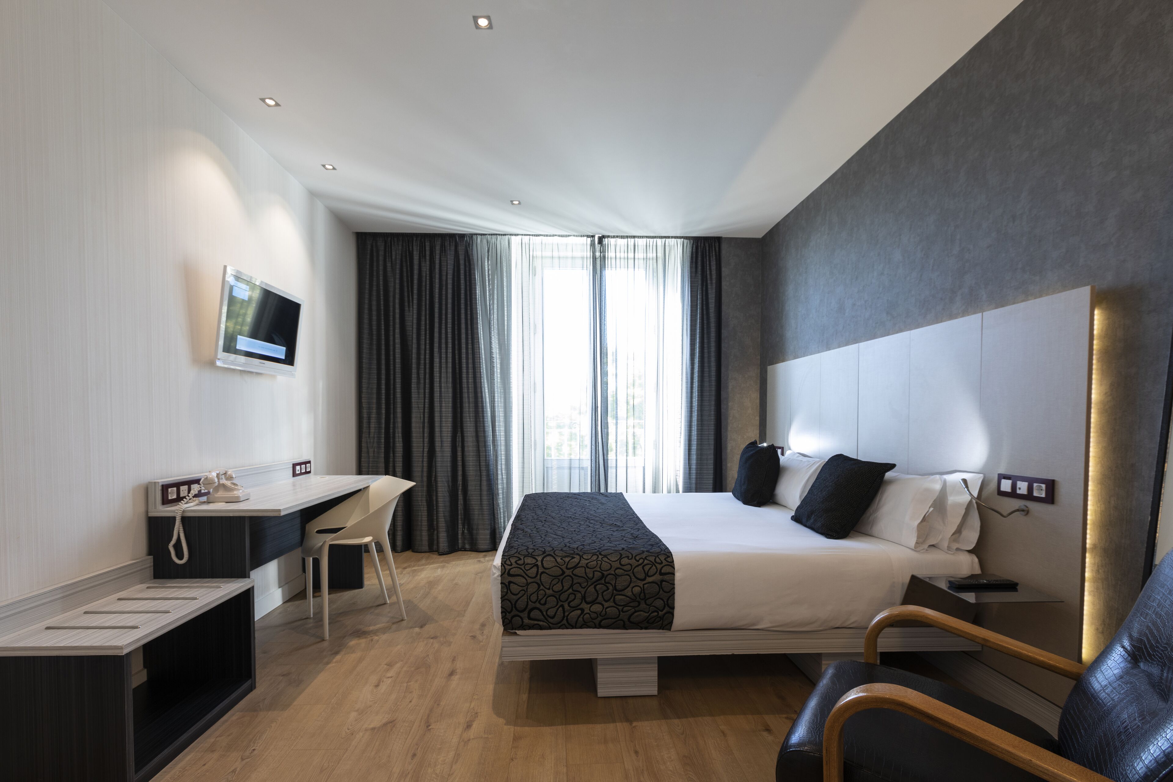 Una habitación de hotel moderna con una cama grande, un escritorio, una silla y una televisión.
