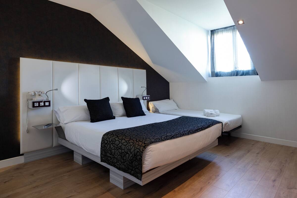 A modern bedroom with a large bed, bedside tables, and a window.