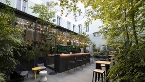 An indoor garden café with a central bar, seating areas, and potted plants. - Petit Palace Santa Bárbara (Madrid)