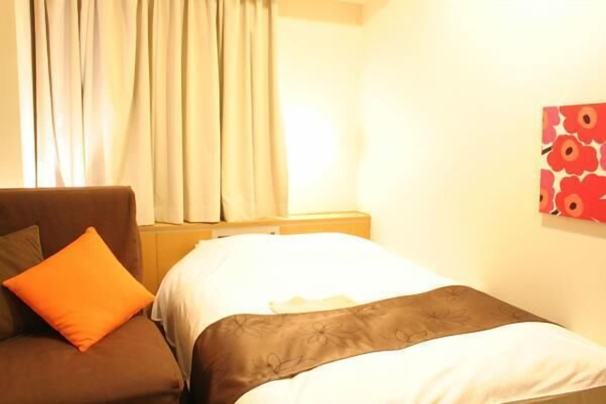 A hotel room with a bed, a sofa, and a painting on the wall.