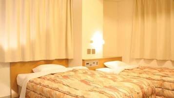 Quarto de hotel com duas camas, cortinas bege, mesa de cabeceira com abajur e painel de controle fixado na parede.