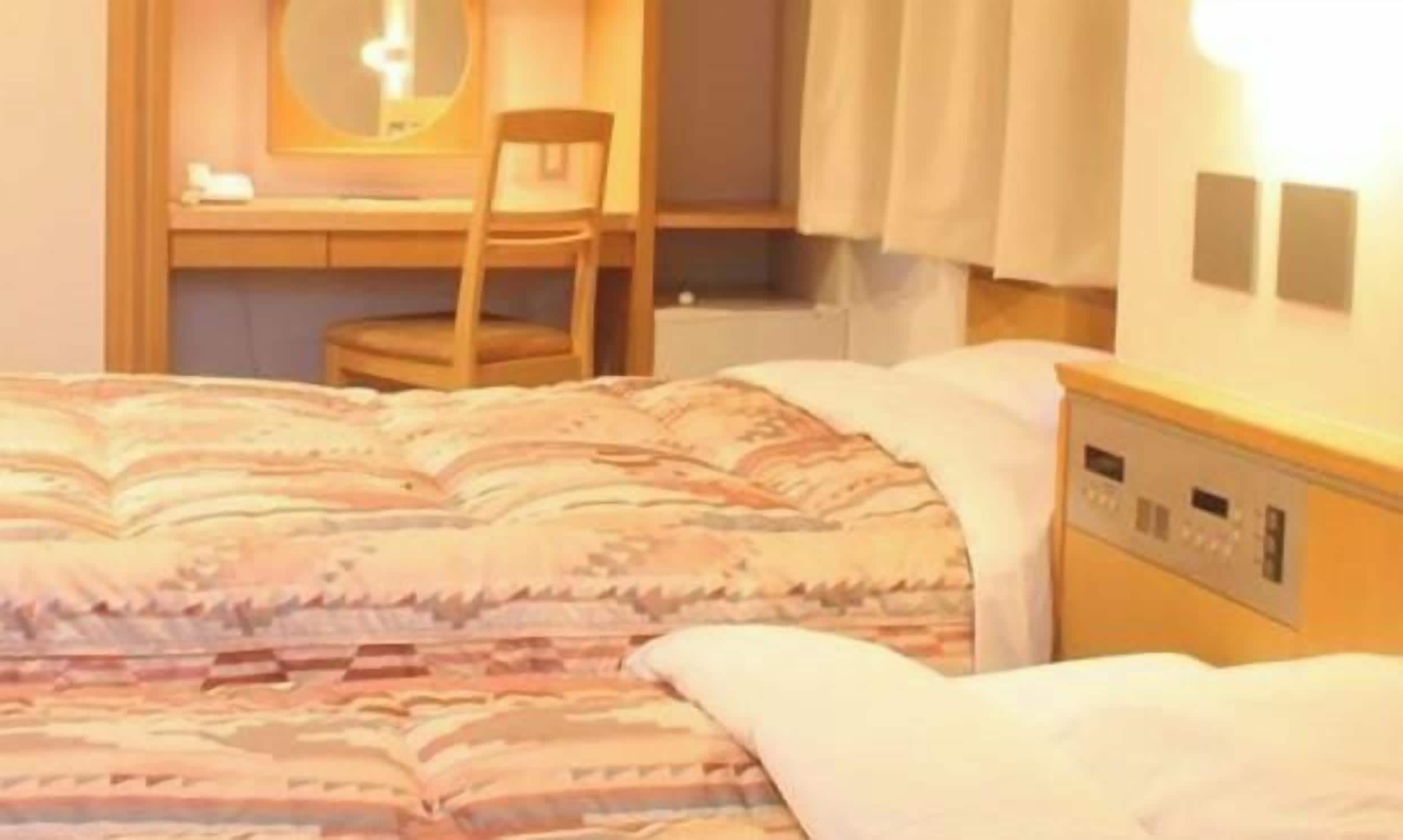 Una habitación de hotel con cama, escritorio, silla y mesita de noche.
