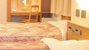 Una habitación de hotel con cama, escritorio, silla y mesita de noche.