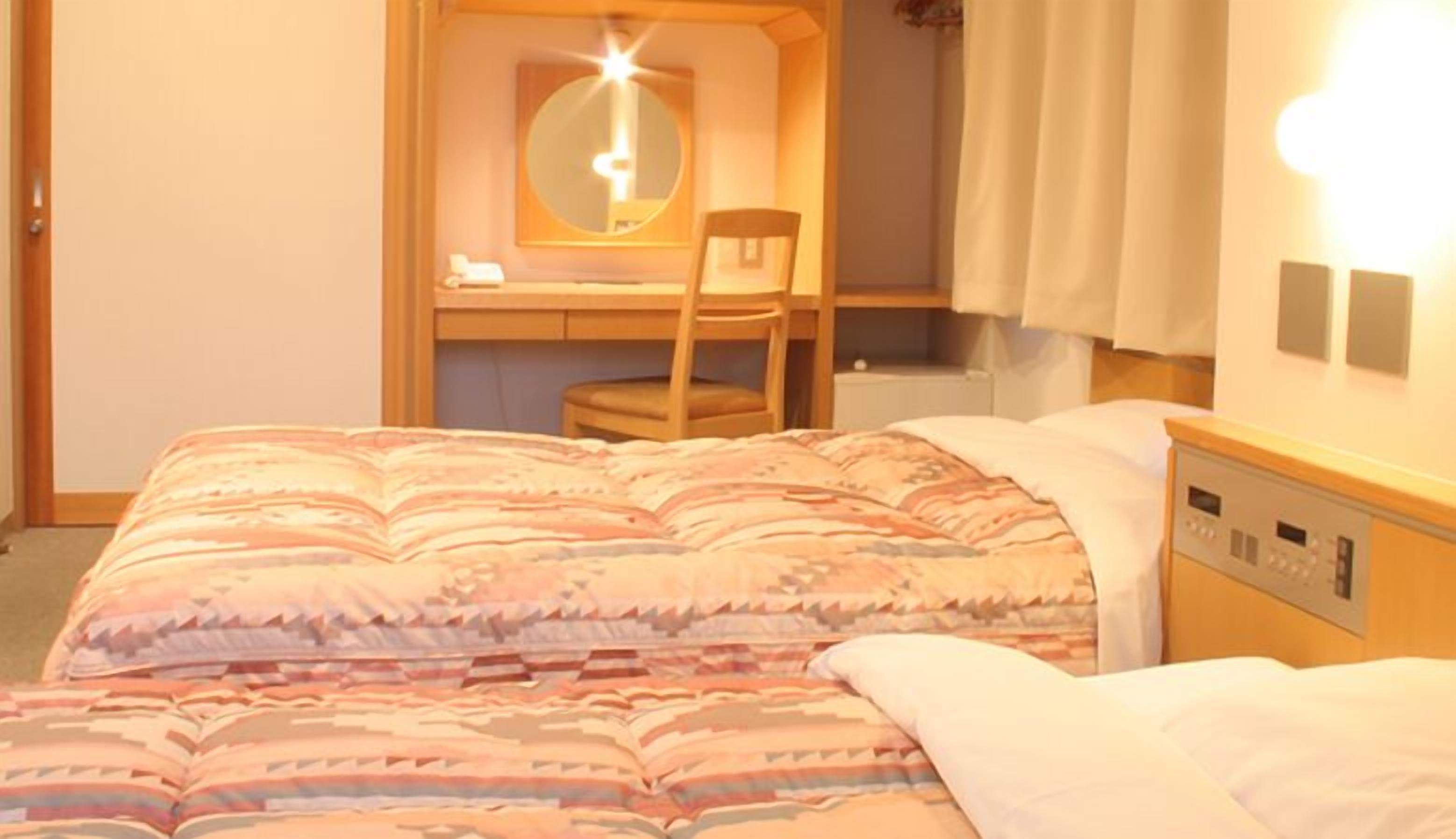 Una camera da letto con un letto, una scrivania, una sedia e un comodino.