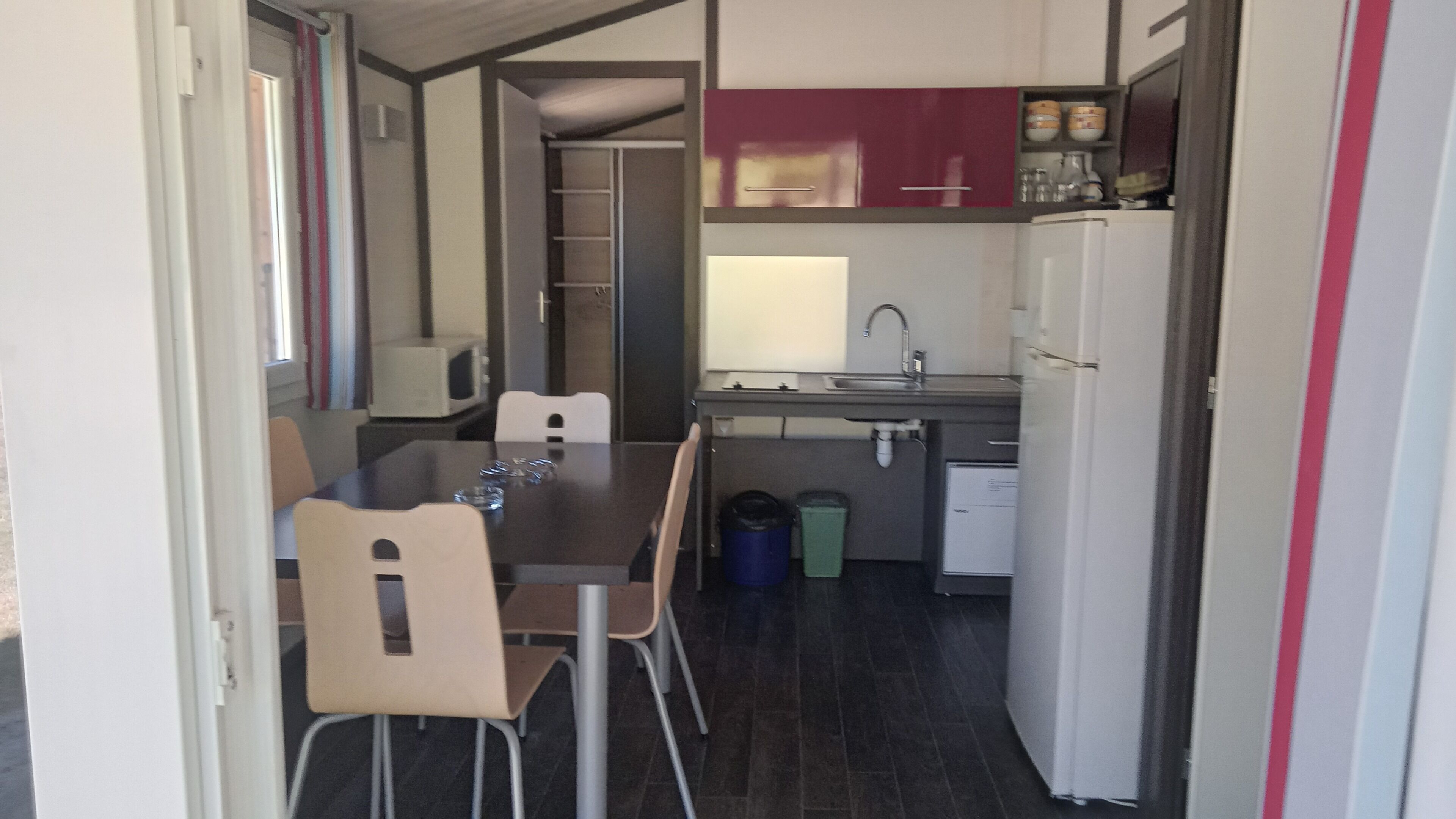 A compact kitchen with a dining table, chairs, a microwave, a sink, and a refrigerator.