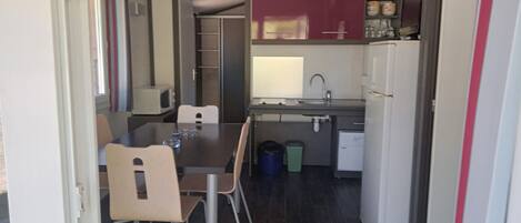 A compact kitchen with a dining table, chairs, a microwave, a sink, and a refrigerator.