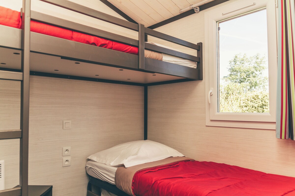 A bunk bed room with a window and a view of greenery outside.