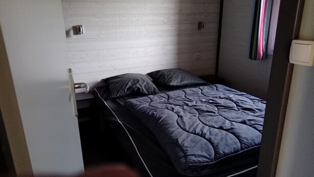A small, single-bed room with a grey wooden wall, a pull-out bed, and a bedside table. - Terres de France - Les Hameaux de Pomette (Marminiac)