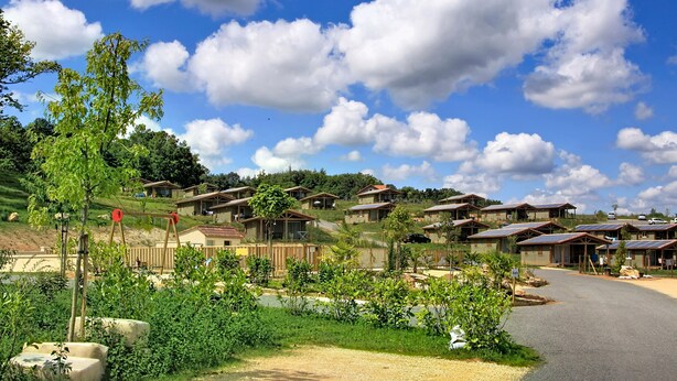 A residential area with multiple houses, a dirt road, and greenery. - Terres de France - Les Hameaux de Pomette (Marminiac)