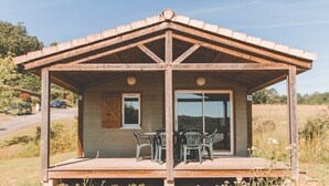 A wooden cabin with a covered patio, a sliding glass door, and a number '24' sign. - Terres de France - Les Hameaux de Pomette (Marminiac)