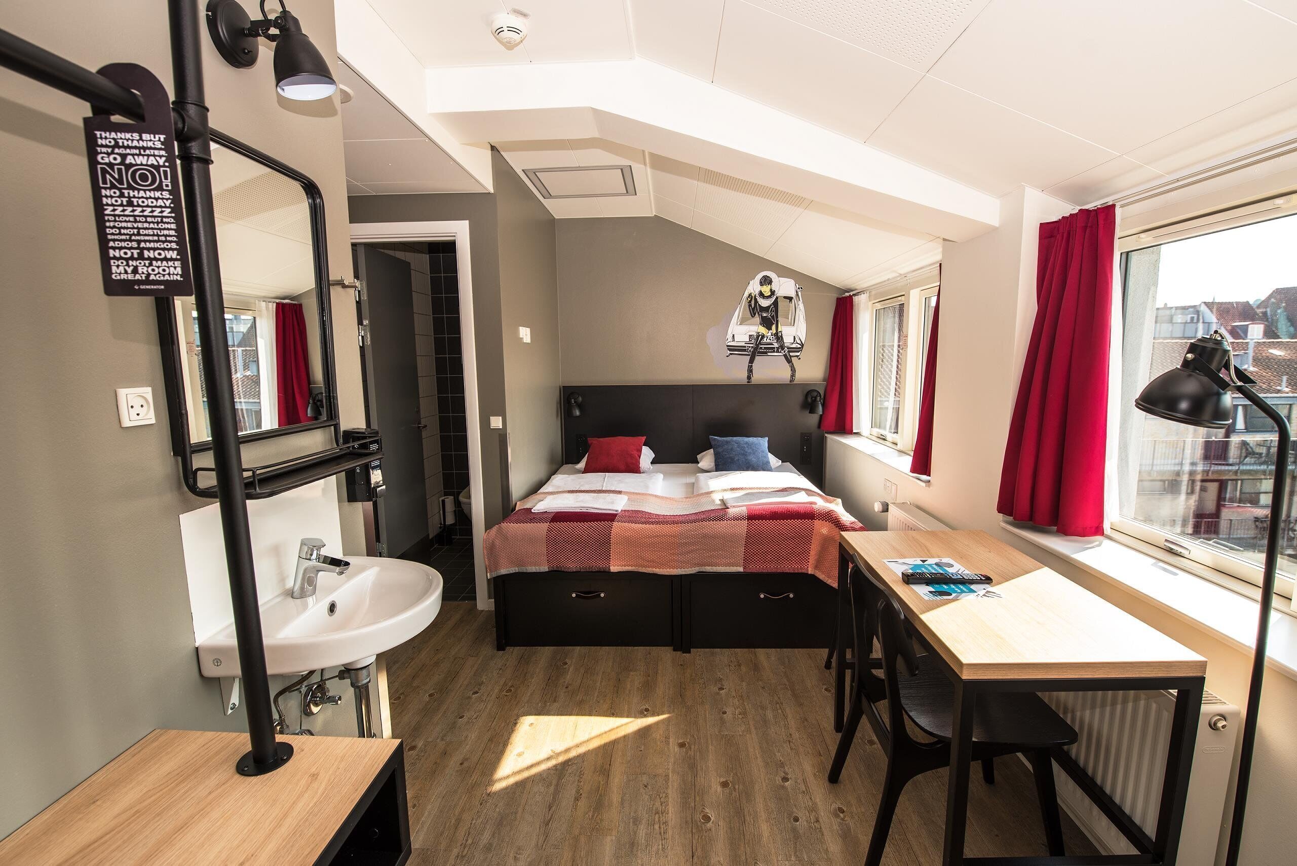 A compact bedroom with a bed, a desk, and a window.