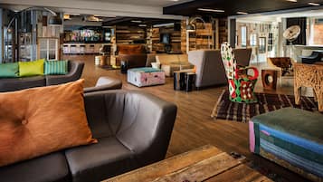A modern lounge area with leather sofas, a bar in the background, and a mix of wooden and upholstered furniture.