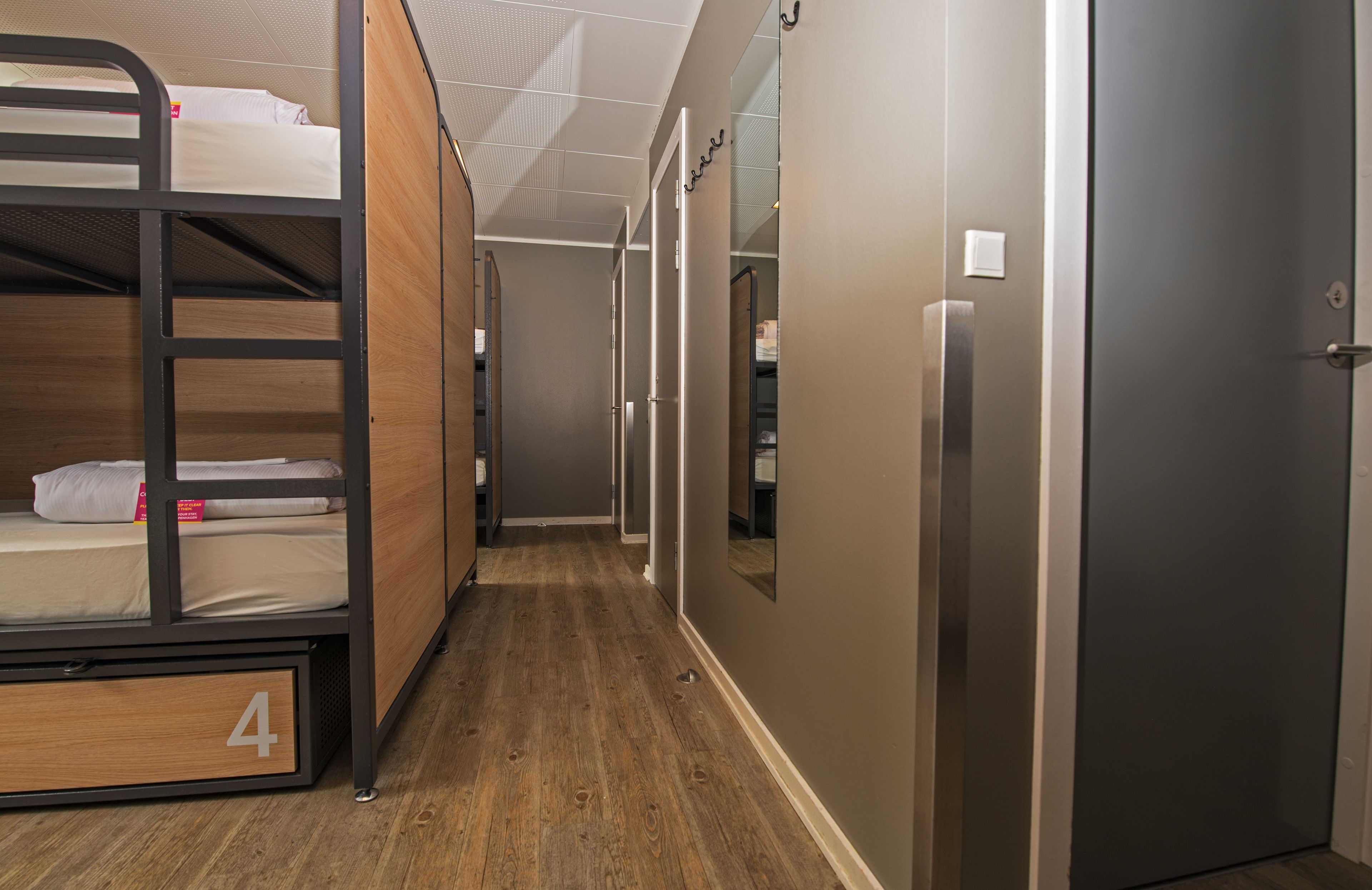 A corridor with bunk beds, a door, and a hallway leading to another room.